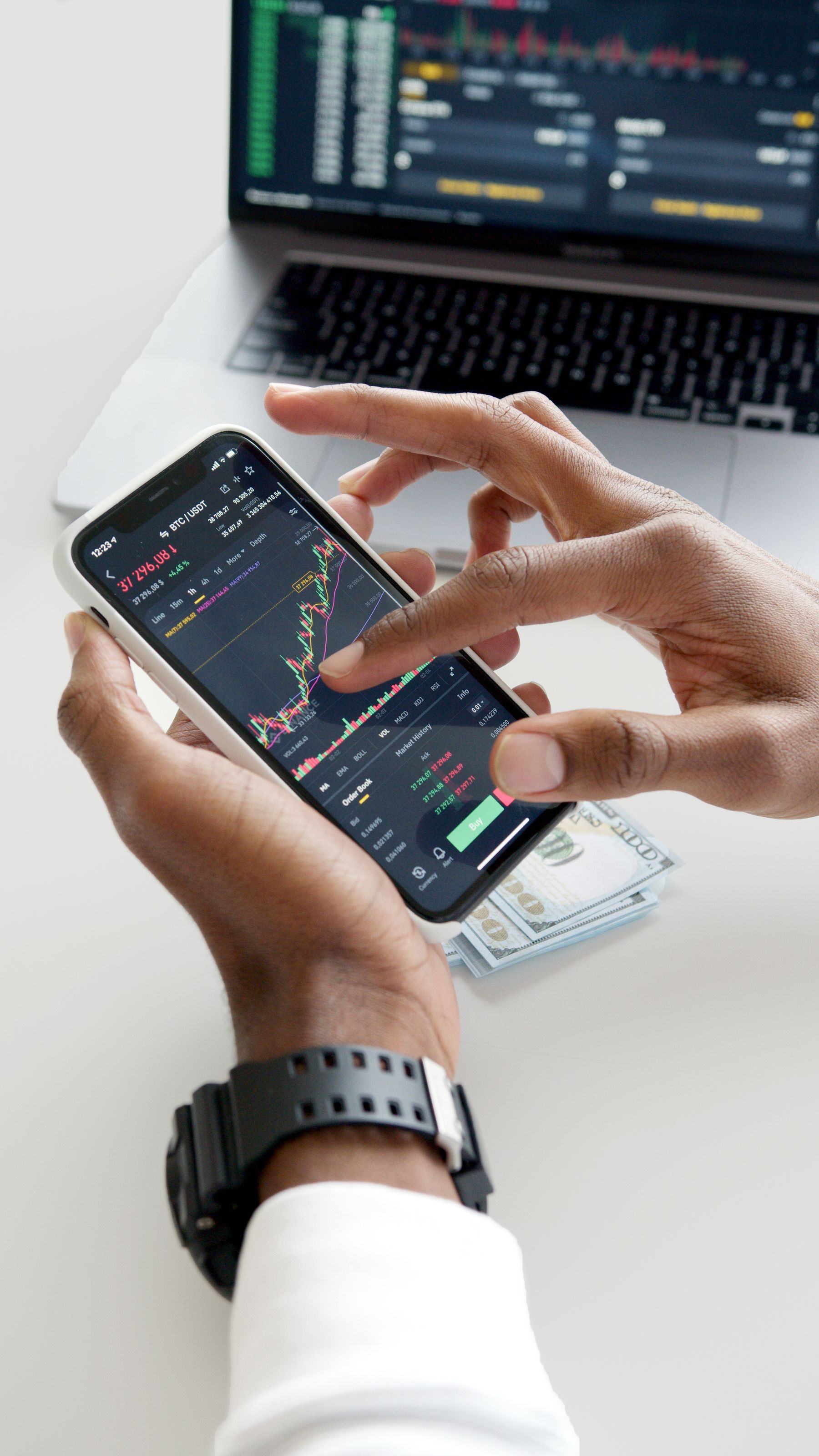 Trader executing orders on a smartphone and laptop